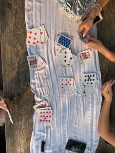 people are playing cards on a table with silver foil covering them and one person is holding a cell phone