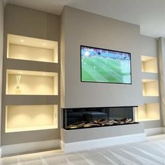 a television mounted on the wall above a fireplace in a living room with built - in shelving