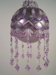 a purple ornament hanging from the ceiling with beads and crystals on it's sides