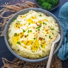 mashed potatoes with butter and parsley in a bowl on a blue tablecloth