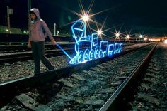 a woman standing on train tracks next to a sign that reads the blue light district