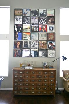 a dresser with many pictures on the wall above it and a lamp next to it