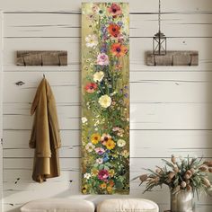 a painting hanging on the side of a wall next to a vase with flowers in it