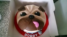 a cake shaped like a dog in a box with its mouth open and tongue out