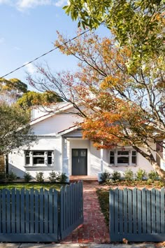 a white house with a blue gate and trees