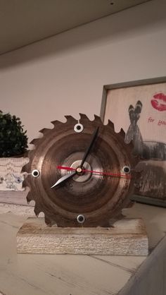 a clock that is sitting on top of a table next to some pictures and trees