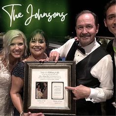 a group of people standing next to each other holding up a framed photo with the words, the johnsons