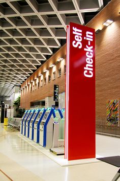 the check in counter at an airport is red and blue with white lettering on it