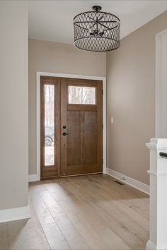 an empty entryway with a wooden door and light fixture hanging from it's ceiling