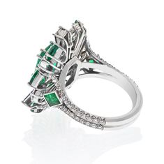 Unveiling the Elegance: Platinum Cocktail Ring with a Radiant Green Emerald Prepare to be captivated by a piece of artistry that transcends time and trends, a platinum cocktail ring designed to exude the epitome of luxury and grace.**The Crown Jewel: A Green Colombian Emerald Masterpiece**At the heart of this ring lies an exquisite green emerald, a resplendent gemstone of 2.92 carats. This central emerald is no ordinary stone; it's a flawless representation of nature's grandeur. But this is just the beginning of the story.**A Symphony of Gemstones: Emeralds and Diamonds**The emerald centerpiece is surrounded by a harmonious arrangement of different shapes of deep, richly colored emeralds. This symphony of shapes and colors adds an unmistakable uniqueness to the design, making it a true col Luxury Marquise Emerald Ring, Luxury Open Emerald Ring With Prong Setting, Luxury Open Emerald Ring For Wedding, Luxury Open Emerald Wedding Ring, Luxury Platinum Emerald Ring With Halo Setting, Luxury Marquise Emerald Ring With Prong Setting, Platinum Gemstone Ring For Evening, Evening Platinum Rings With Brilliant Cut, White Gold Ring With Center Stone For Evening