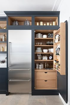 an open refrigerator in a kitchen with lots of cupboard space and shelves on the side