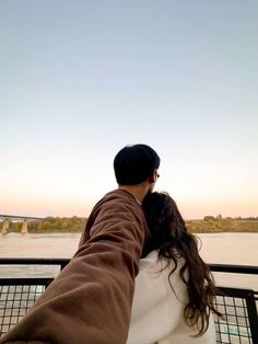 a man and woman are looking out at the water from a boat on the river