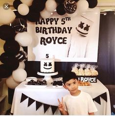 a young boy standing in front of a birthday cake