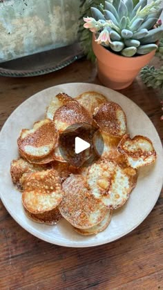 a white plate topped with pancakes covered in powdered sugar next to a potted plant