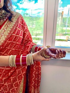 a woman in a red and gold sari holding a plate