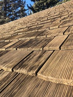 the roof of a building with wooden slats on it's sides and trees in the background