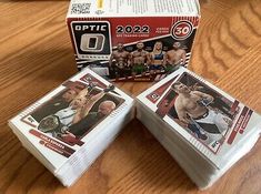 three unopened wrestling cards sitting on top of a wooden table