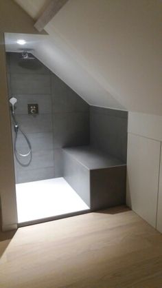 an attic bathroom with white walls and wood flooring is seen from the doorway to the shower area