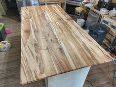 a kitchen counter made out of wood in a room filled with other appliances and cabinets