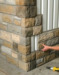 a man that is standing next to a brick wall with tools in front of him