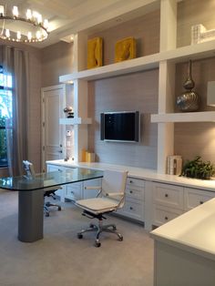 a room with a desk, chair and television on the wall in it's center