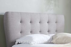 the headboard of a bed with white pillows