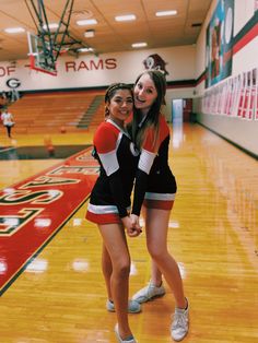 two cheerleaders posing for a photo in the gym