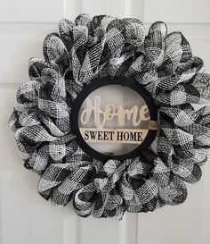 a black and white mesh wreath with the words home sweet home on it hanging on a door