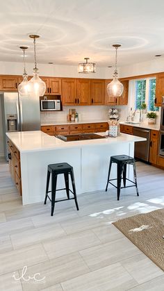 a kitchen with two stools in front of the island and an open floor plan