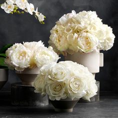 three vases filled with white flowers on top of a table