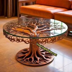 a glass table with a tree design on the top and bottom, sitting in front of a couch