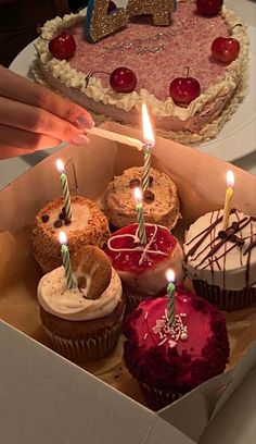 a box filled with lots of cupcakes and lit candles on top of them