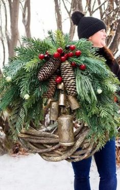 a woman carrying a wreath and bells in the snow