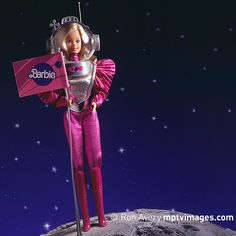 a barbie doll holding a flag on top of the moon with stars in the background