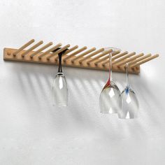 three wine glasses hanging from a wooden rack on the wall next to a white wall