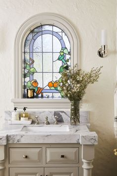 a bathroom with a large window and marble counter top, along with a sink in front of it