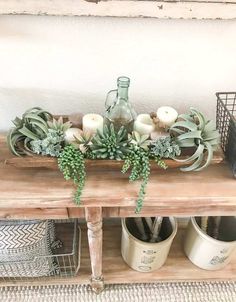 an arrangement of succulents and candles on a table