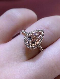 a close up of a person's hand holding a ring with a brown diamond