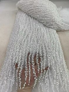 white beaded fabric on the ground with one hand and two feet in front of it