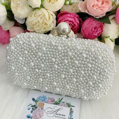 This luxurious encrusted pearl bridal clutch never fails to turn heads with its understated elegance and classic design. Adorned with varying sized ivory pearls and enhanced with a large creamy pearl clasp, this bridal clutch is the very picture of refinement. This elegant bridal clutch features rose gold trim, attachable chain and large enough for your phone. Complete your list of must-have wedding accessories with the ultimate bridal accessory to finish off your look and storing your wedding d Pearl White Clutch For Wedding, Silver Bag With Pearl Embroidery For Events, Rectangular Pearl Clutch For Wedding, Silver Bags With Pearl Embroidery For Events, Silver Bags With Pearl Embroidery In Rectangular Shape, Beaded Pearl White Clutch For Wedding, Silver Clutch With Pearl Embroidery For Party, Beaded Pouch Clutch For Wedding, Rectangular Beaded Evening Bag For Wedding