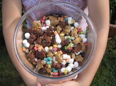 a person holding a glass bowl filled with cereal and marshmallows in their hands