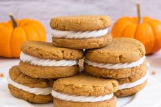 a stack of cookies sitting on top of a white plate next to two pumpkins