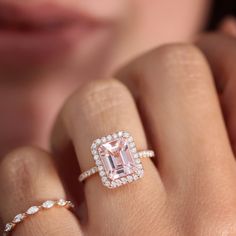 a woman's hand holding an engagement ring with a pink diamond in the center