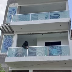 a man standing on the balcony of a building painted with blue and white swirls