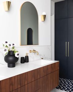 a bathroom with marble counter tops and black vases on the vanity next to it