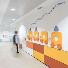 a blurry photo of a person walking in an office hallway with colorful letters on the wall