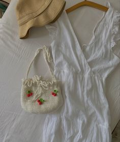 a white dress and straw hat laying on top of a bed next to a purse