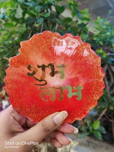 a person holding up a red frisbee with writing on it