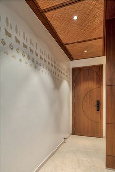 an empty room with a wooden door and decorative wall art on the walls, along with white flooring