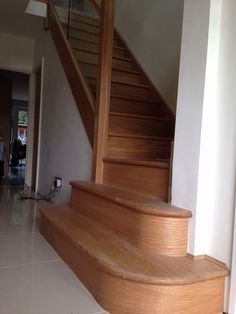 a wooden stair case next to a white tiled floor